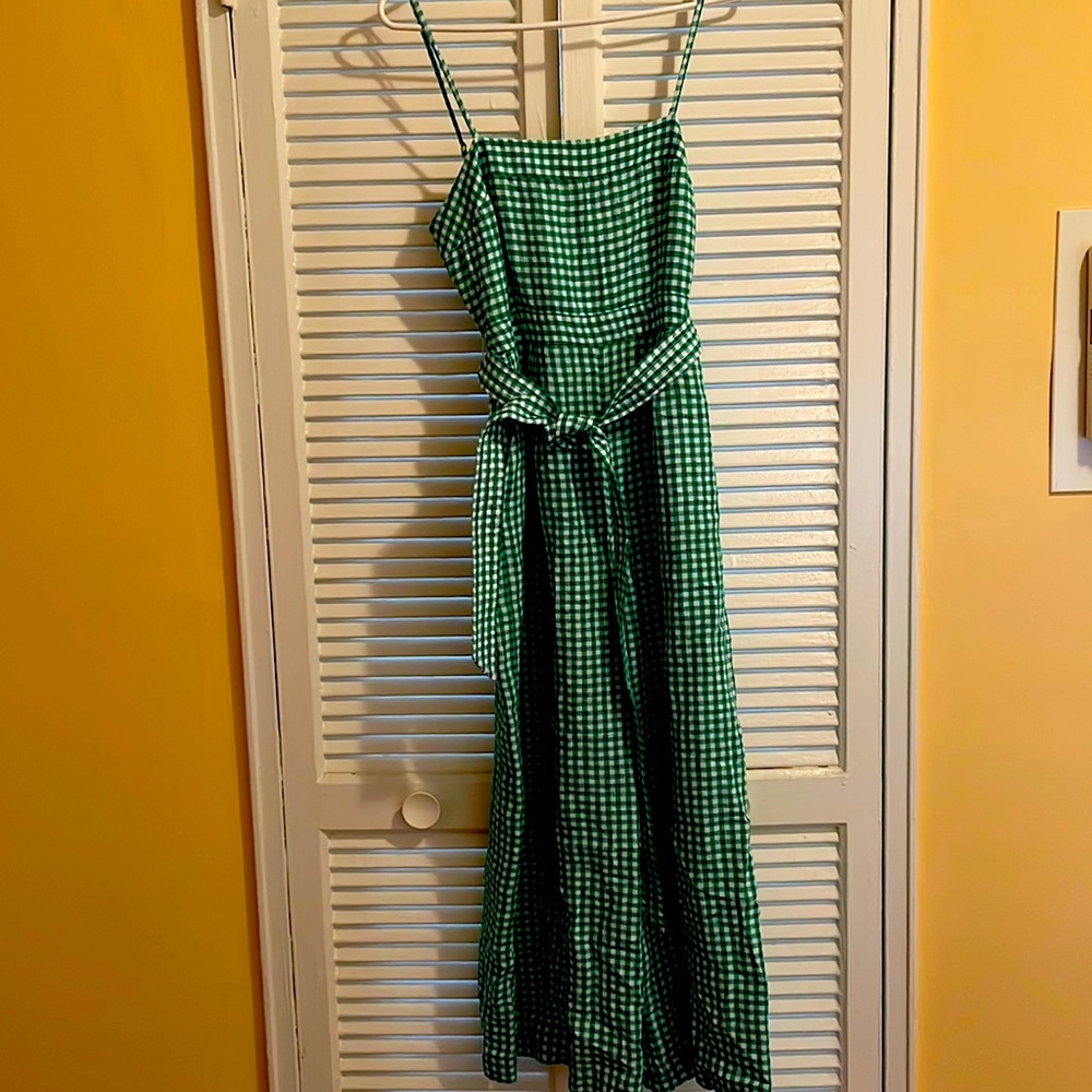 Tie waist linen jumpsuit in gingham. Pant leg is above ankles.